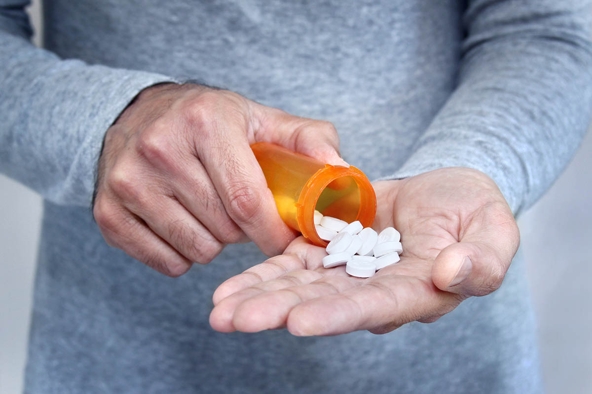 Hands of man holding pill bottle with pills on hand